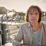 woman in white jacket sitting on bench during daytime