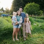 Family standing in a lush green field with tractor.